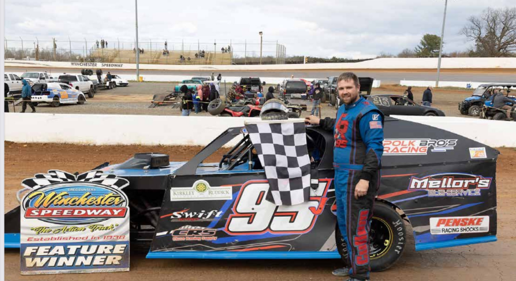 Justin Cullum stands next to his race car on the track.