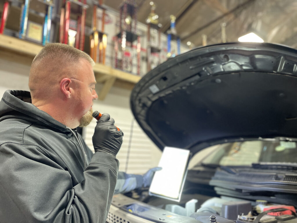 Mechanic inspecting vehicle with tablet.